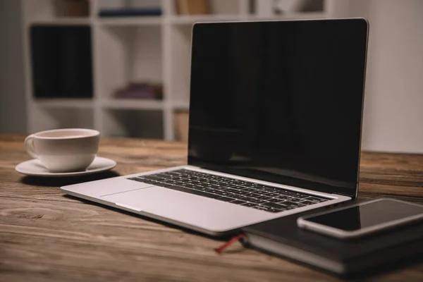 Laptop, smartphone e xícara de café na mesa de madeira — Fotografia de Stock