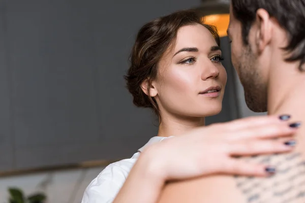 Beautiful tender girl looking into eyes and embracing boyfriend with tattoo — Stock Photo