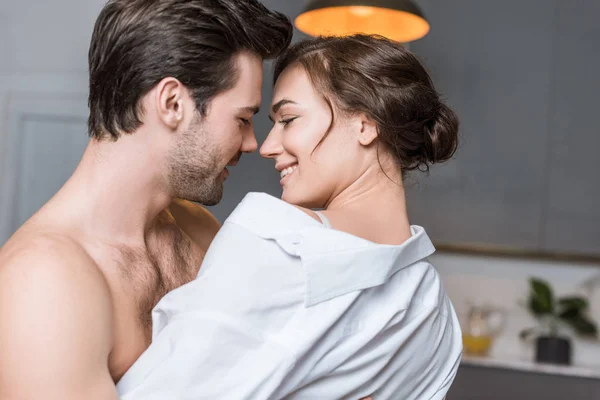 Adulto concurso casal abraçando e sorrindo em casa — Fotografia de Stock