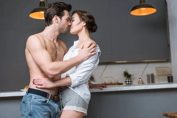 Hombre y mujer adultos besándose en la cocina con los ojos cerrados - foto de stock