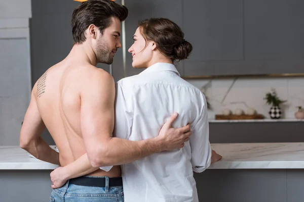 Pareja adulta abrazando y sonriendo en casa - foto de stock