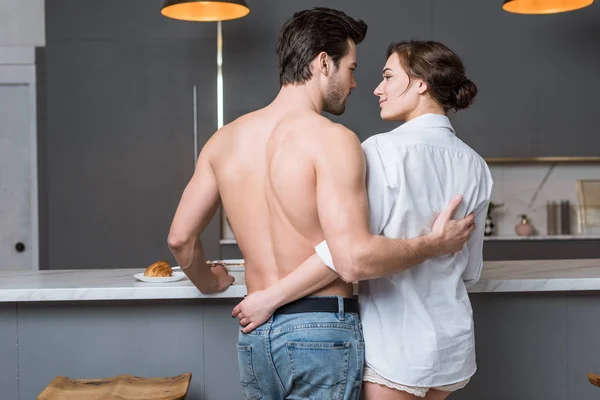 Vue arrière du couple adulte embrassant et souriant à la cuisine — Photo de stock