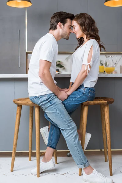 Alegre pareja sonriendo con los ojos cerrados mientras toma de la mano en la cocina - foto de stock