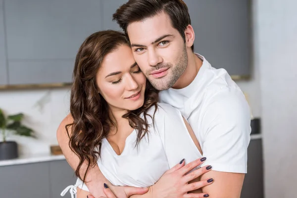 Красивий чоловік обіймає жінку закритими очима вдома — стокове фото
