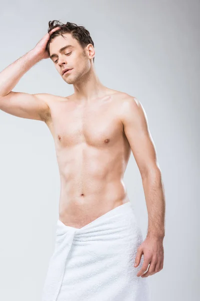 Handsome shirtless macho posing in towel isolated on grey — Stock Photo