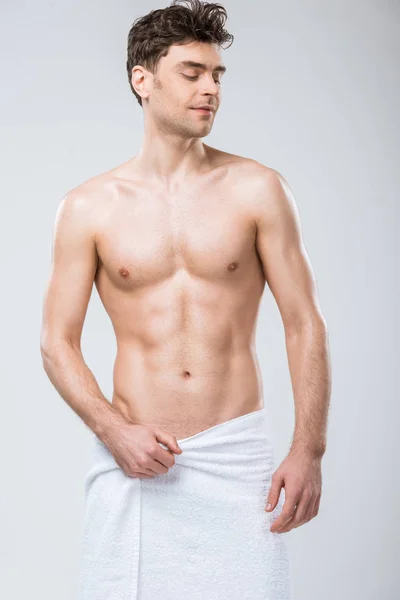 Sexy shirtless smiling man posing in towel isolated on grey — Stock Photo