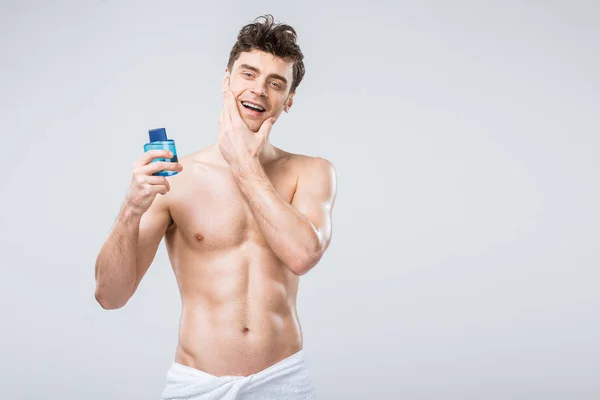 Happy shirtless man holding bottle with cologne, isolated on grey — Stock Photo