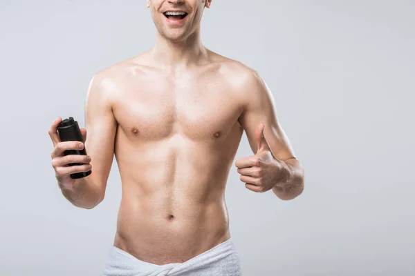 Ausgeschnittene Ansicht eines hemdlosen Mannes, der Deo in der Hand hält und Daumen nach oben zeigt, isoliert auf grau — Stockfoto