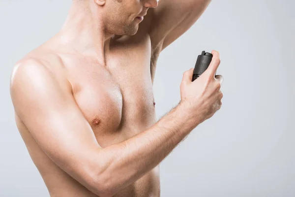 Vista recortada de hombre sin camisa rociando desodorante, aislado en gris - foto de stock