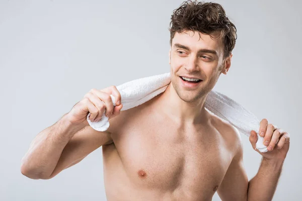 Bonito sorridente homem segurando branco toalha isolado no cinza — Fotografia de Stock