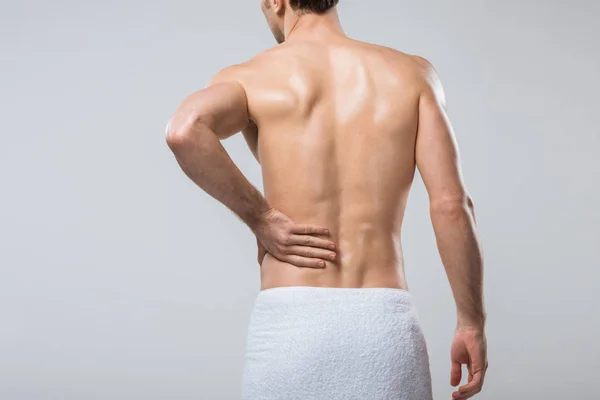 Visão traseira do jovem que sofre de dor nas costas, isolado em cinza — Fotografia de Stock