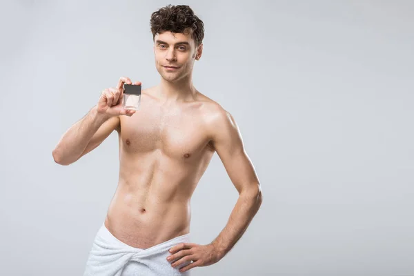 Hemdloser Mann mit einer Flasche Parfüm, isoliert auf grau — Stockfoto