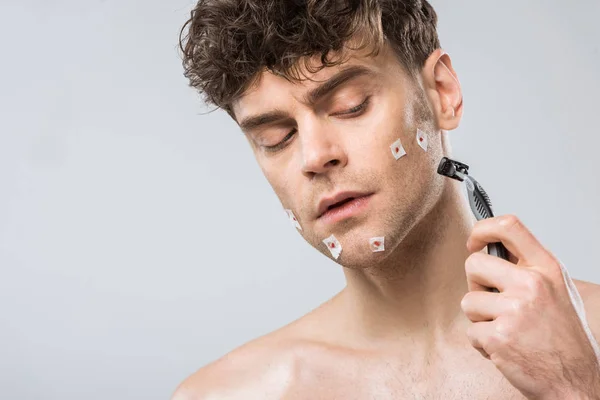 Hombre guapo con afeitadora después de afeitarse mal, aislado en gris - foto de stock