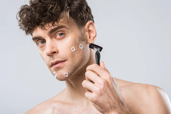 Людина тримає бритву після поганого гоління, ізольована на сірому — стокове фото