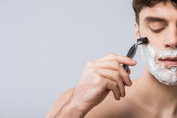 Guapo joven espuma en el afeitado de la cara con afeitadora, aislado en gris - foto de stock
