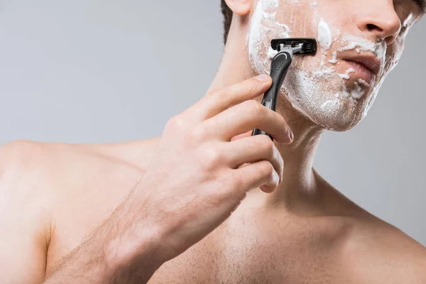 Vista recortada de la espuma del hombre en el afeitado facial con afeitadora, aislado en gris - foto de stock