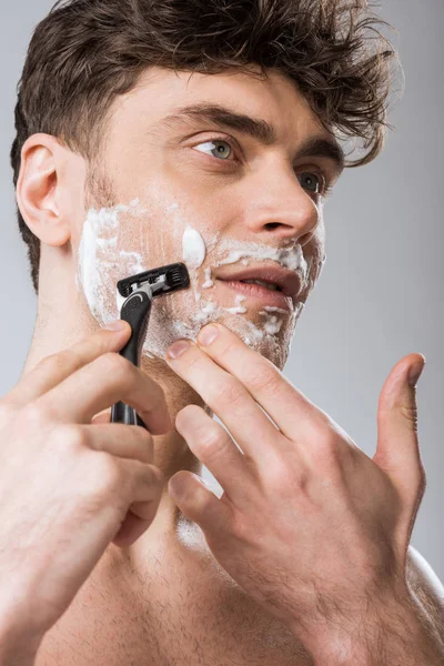Bell'uomo schiuma sul viso rasatura con rasoio, isolato su grigio — Foto stock