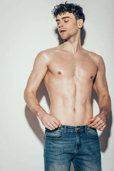 Sexy shirtless stylish man in jeans posing on grey — Stock Photo