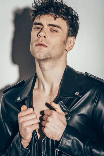 Portrait of sexy man posing in black leather jacket on grey — Stock Photo