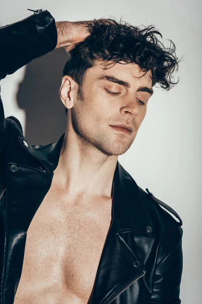 Красивий сексуальний чоловік позує в чорній шкіряній куртці на сірому — стокове фото
