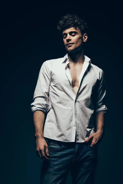 Модний красивий чоловік позує в білій сорочці ізольовано на темно-сірому — стокове фото