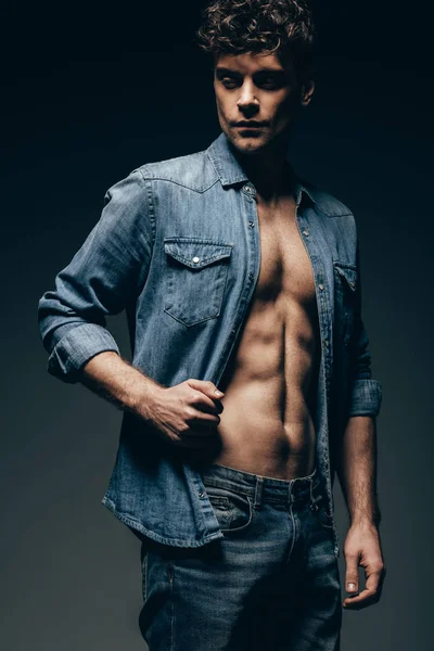 Bellissimo uomo sexy posa in camicia di jeans isolato su grigio — Foto stock