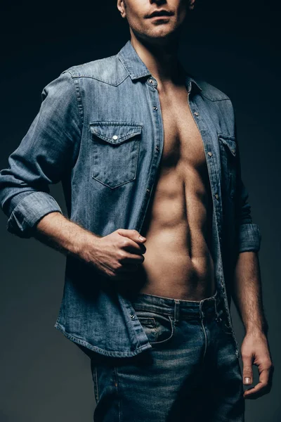 Обрізаний вид сексуального чоловіка позує в джинсовій сорочці ізольовано на сірому — стокове фото