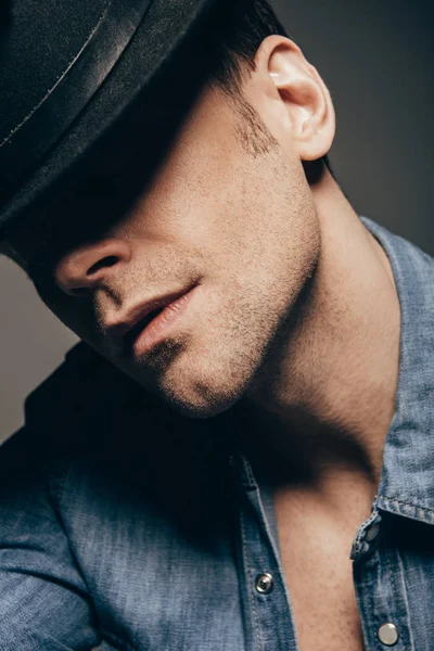 Retrato de hombre guapo posando con sombrero aislado sobre gris oscuro - foto de stock