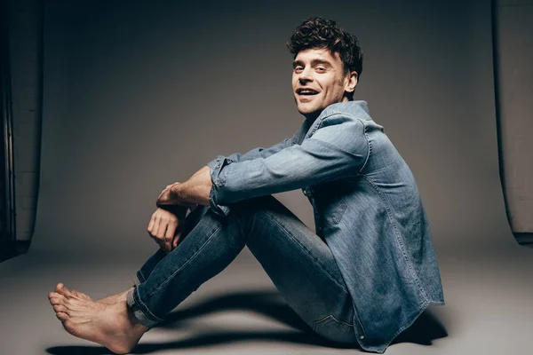 Glücklich barfuß sexy Mann posiert in Jeans Kleidung auf dunkelgrau — Stockfoto