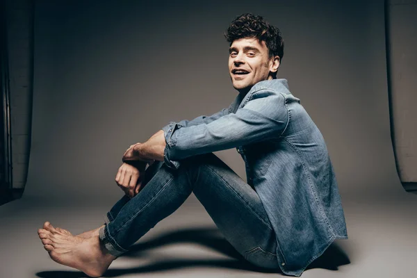 Felice uomo sexy a piedi nudi in posa jeans vestiti di grigio scuro — Foto stock