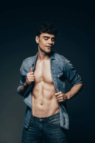 Sexy macho posando en jeans ropa aislada en gris oscuro - foto de stock