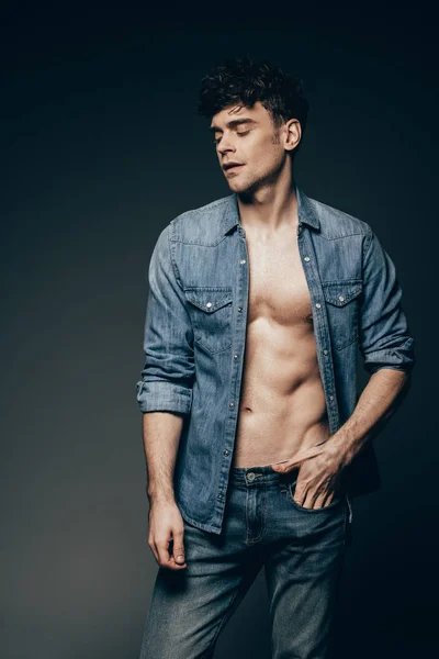 Bonito sexy homem posando no jeans roupas isolado no escuro cinza — Fotografia de Stock