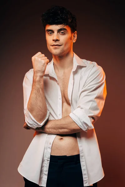 Schöner nachdenklicher Mann posiert in weißem Hemd, isoliert auf braun — Stockfoto