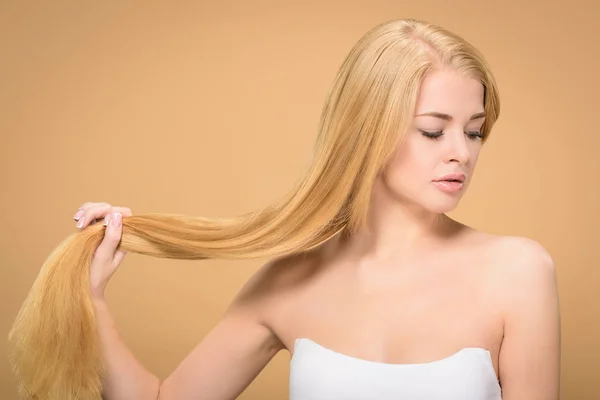 Attractive young woman holding blonde hair in hand — Stock Photo