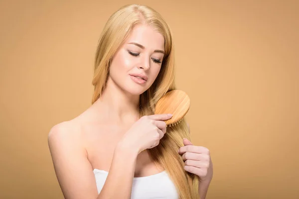 Sensual joven mujer cepillando el pelo rubio con suavidad sonrisa - foto de stock