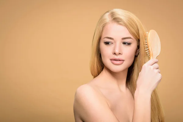 Studio shot of attractive young woman brushing hair — Stock Photo