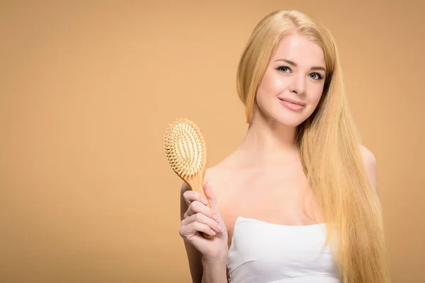 Jolie femme blonde tenant une brosse à cheveux en bois — Photo de stock