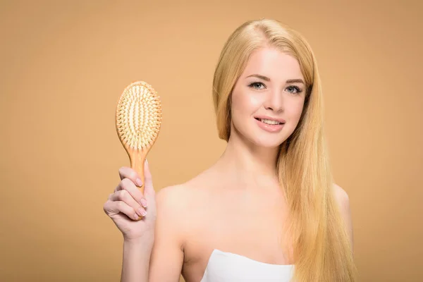 Ragazza affascinante in possesso di spazzola per capelli in legno con sorriso sincero — Foto stock