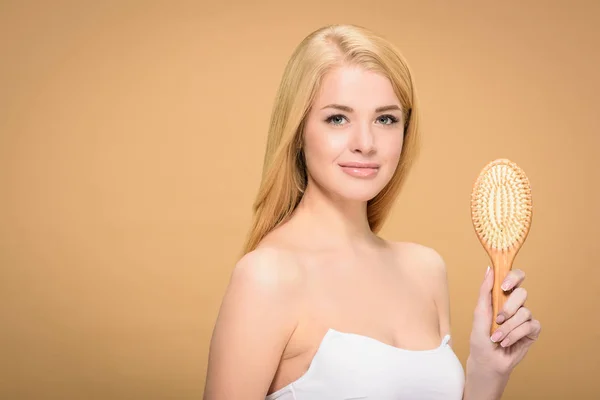 Ragazza attraente in posa con spazzola per capelli in legno e sorridente — Foto stock