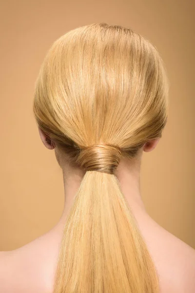 Vista posteriore della giovane donna bionda con lunghi capelli lisci lisci isolati sul beige — Foto stock