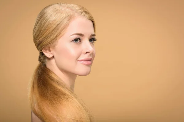 Красива усміхнена гола блондинка з довгим волоссям дивиться ізольовано на бежевому — стокове фото