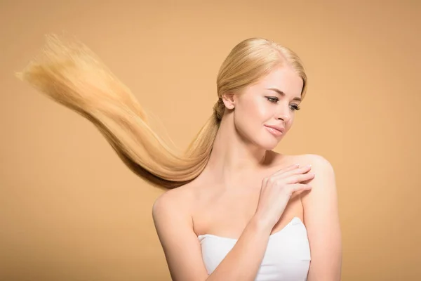 Schöne blonde Frau mit langen Haaren, die isoliert von beige wegschaut — Stockfoto