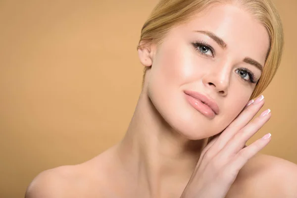 Beautiful tender young woman touching face and looking at camera isolated on beige — Stock Photo