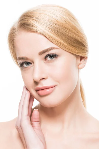 Close-up view of beautiful young blonde woman touching face and looking at camera isolated on white — Stock Photo