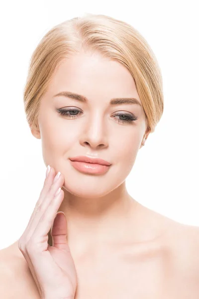 Beautiful young blonde woman with perfect skin touching face with hand and looking down isolated on white — Stock Photo