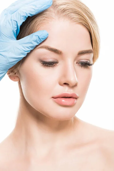 Cropped shot of cosmetologist touching forehead of beautiful young woman isolated on white — Stock Photo