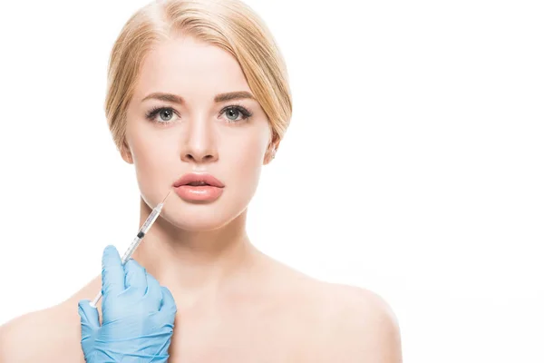 Beautiful naked woman receiving beauty injection in lips and looking at camera isolated on white — Stock Photo