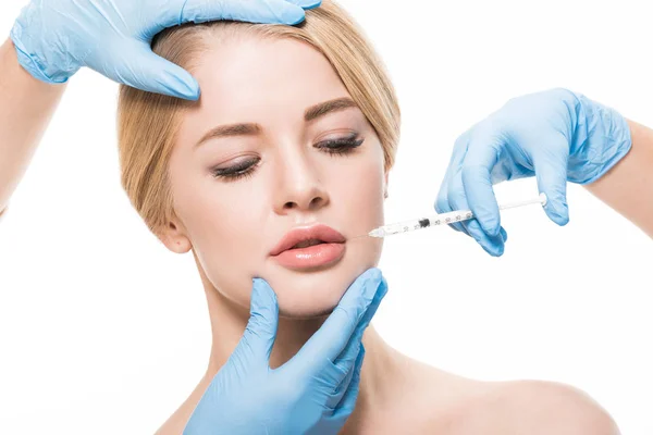 Cropped shot of cosmetologists in medical gloves making beauty injection to young woman isolated on white — Stock Photo