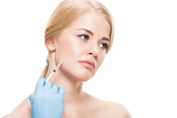 Inyección recortada de cosmetólogo en guante de látex haciendo inyección de belleza a una mujer joven aislada en blanco - foto de stock
