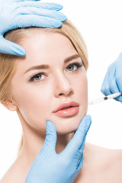 Abgeschnittene Aufnahme von Kosmetikerinnen, die einer jungen Frau Schönheitsinjektionen machen, die isoliert auf Weiß in die Kamera schaut — Stockfoto
